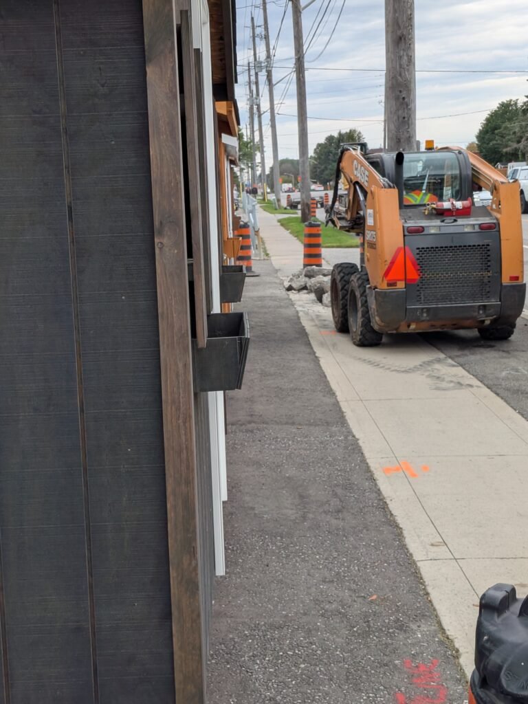 Who Is Paying for Oshawa Sidewalk Work on Bloor Street East? Broken sidewalk concrete and a construction worker near 109 Bloor Street East in Oshawa
