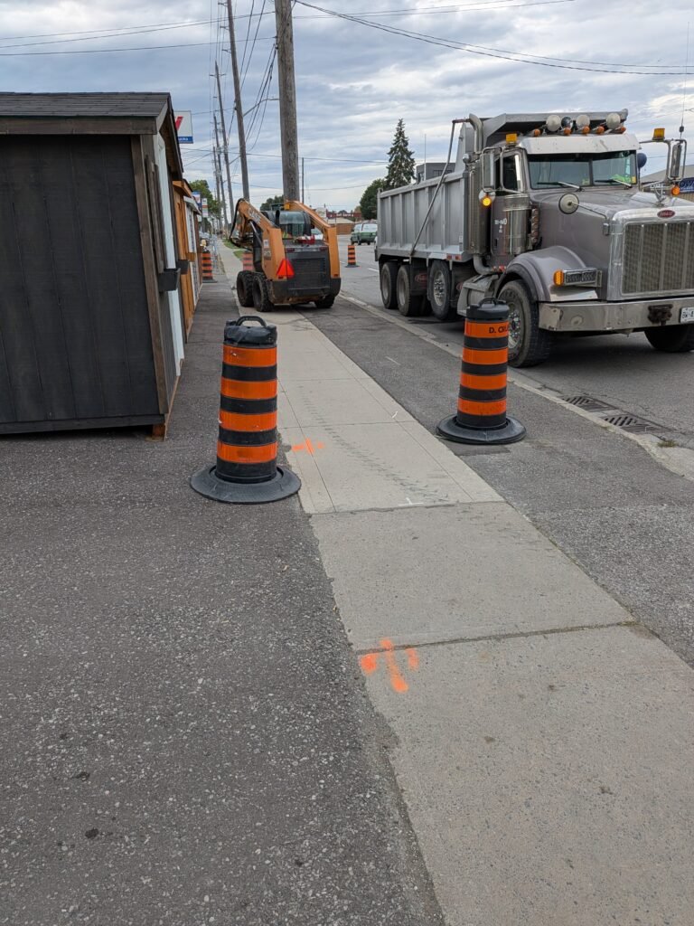 Who Is Paying for Oshawa Sidewalk Work on Bloor Street East? Dump truck, skid-steer and traffic barrels beside sidewalk work on Bloor Street East in Oshawa